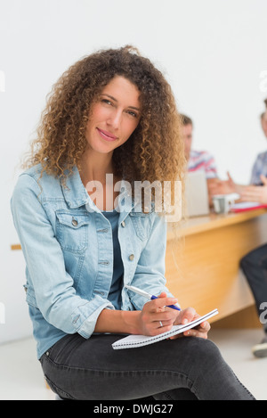 Cheerful designer sitting in front of her colleagues using digital tablet Stock Photo