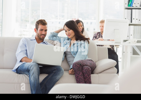 Young smiling designers working on laptop on the couch Stock Photo