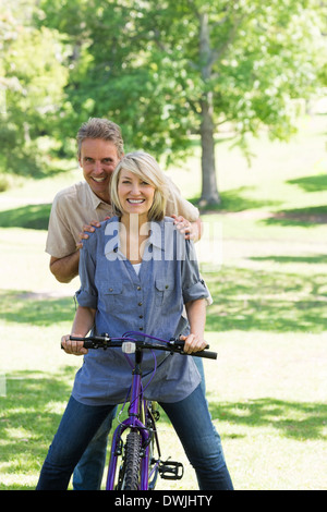 Couple riding bicycle in park Stock Photo