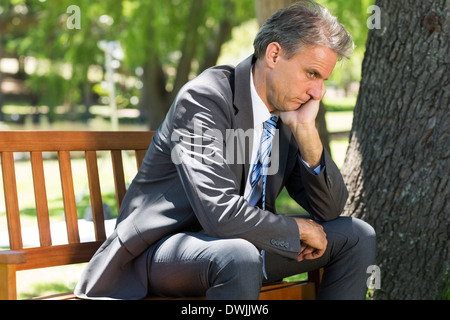 Depressed businessman sitting on park bench Stock Photo