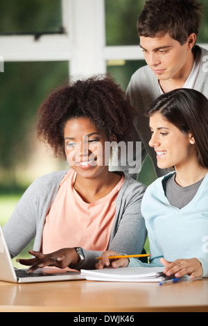 Friends Using Laptop At Desk In Classroom Stock Photo