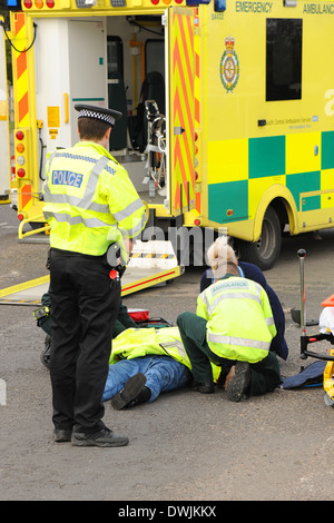 A road traffic accident casualty is tended to by ambulance crew and police officers
