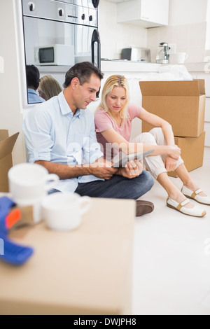 Couple using digital tablet amid boxes in house Stock Photo