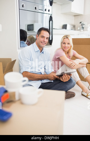 Couple using digital tablet amid boxes in a new house Stock Photo