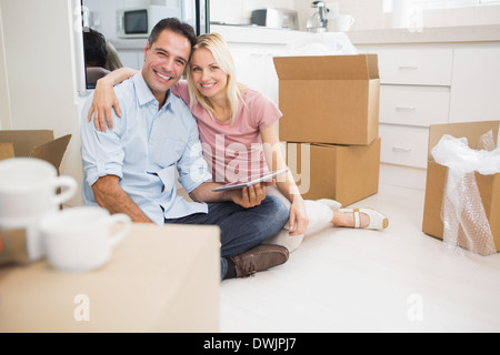Couple using digital tablet amid boxes in new house Stock Photo