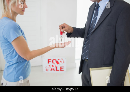 Real estate agent passing house key to woman Stock Photo