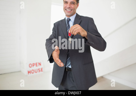 Businessman offering a handshake while holding up keys Stock Photo