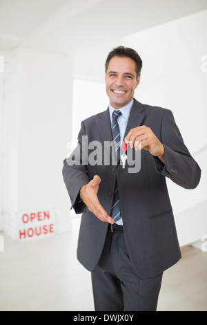 Businessman offering a handshake while holding up keys Stock Photo