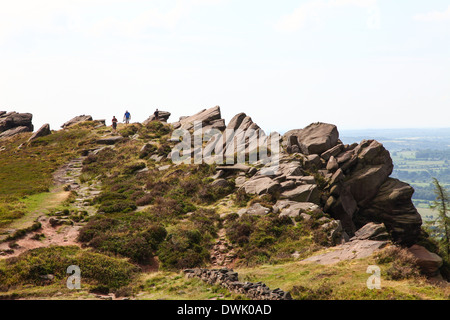 Three people climbing and walking on Hen Cloud at The Roaches Staffordshire Peak District Stock Photo