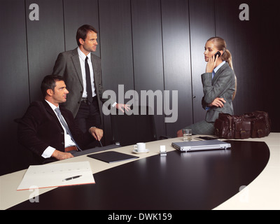 businessman explaining to businesswoman at office sitting on table talking on mobile Stock Photo
