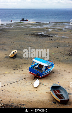 A crew of fishermen unloading the vessel at the seaside during the low tide in Northern Mozambique. Stock Photo