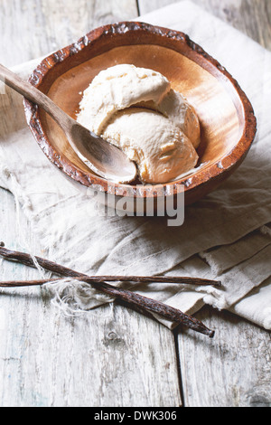 Wooden bowl with vanilla ice cream and vanilla stick on old wooden table Stock Photo