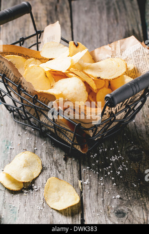 Basket with potato chips with sea salt over old wooden table. Stock Photo