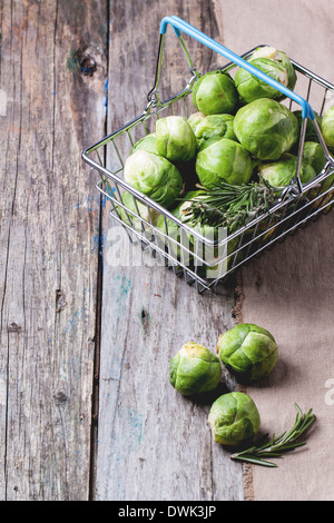 Food basket of brussels sprouts and rosemary on old wooden table. Stock Photo