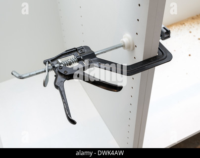 Black clamp securely holding wooden kitchen cabinets together during installation Stock Photo
