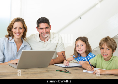 Parents with laptop while children coloring at table Stock Photo