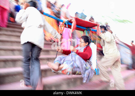 Barsana, India. 8th Mar, 2014. Porters carry a woman to the Laadliji Temple situated atop the hill at Barsana during Lathmaar Holi or Lathmar Holi festival in Barsana. © Subhash Sharma/ZUMA Wire/ZUMAPRESS.com/Alamy Live News Stock Photo