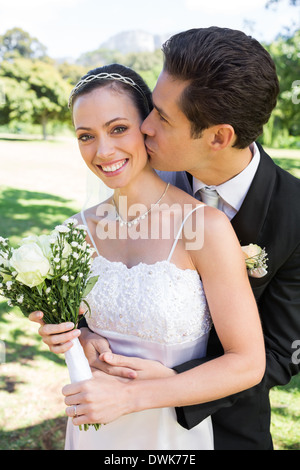 Groom Kissing Bride on Cheek Sitting Outside Stock Photo - Alamy