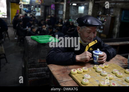 Chongqing. 7th Mar, 2014. A customer enjoys a cup of tea during a Chinese chess game at the Jiaotong Tea House in Jiulongpo District of southwest China's Chongqing Municipality, March 7, 2014. The Jiaotong Tea House, in business for nearly three decades, has become the favourite place to go for many tea lovers as many other tea houses in downtown Chongqing were closed down. Many customers stay here for a whole day, involved in typical tea house entertainments: savouring tea, chatting with others, playing cards and remembering the old times. © Zhou Hui/Xinhua/Alamy Live News Stock Photo