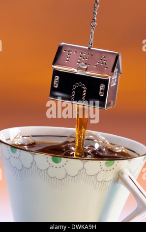 Making a cup of tea with a metal strainer full of tea leaves being dunked in a cup of hot water. Stock Photo