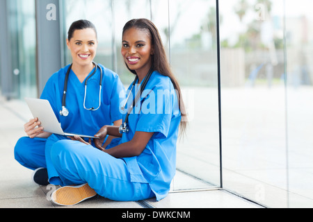 attractive female doctors sitting on the floor using laptop Stock Photo
