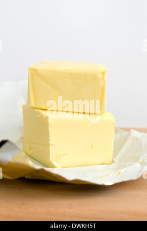 Open pack of butter on wooden chopping board Stock Photo