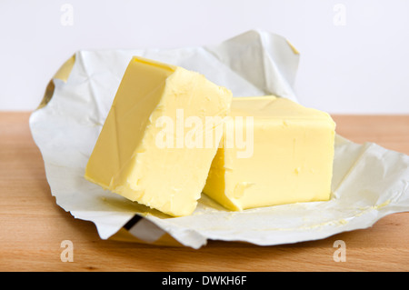 Open pack of butter on wooden chopping board Stock Photo