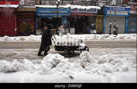 Srinagar, Indian Administered Kashmir. 10 March, 2014 A kashmiri man pushes hand cart   during  snow continuing on second day, the summer capital of Indian administered Kashmir, India. Kashmir valley was Tuesday  cut off from rest of India due to heavy snowfall.( photo by sofi suhail /Alamy Live News) Stock Photo