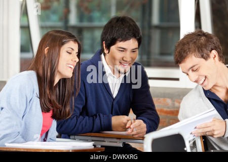 Students Discussing Over Book In Classroom Stock Photo