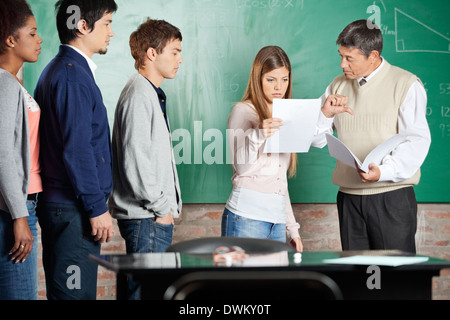 Teacher Gesturing Thumbsdown While Student Looking At Report In Stock Photo