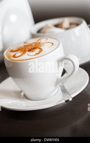 White cup of cappuccino stands on dark wooden table Stock Photo