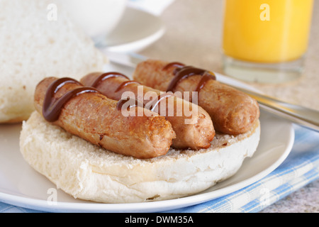 Sausage sandwich or sausage bap topped with brown sauce selective focus on front sausage Stock Photo