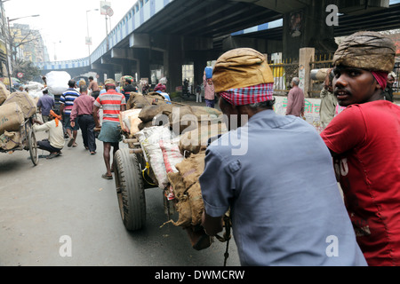 Hard working Indians pushing heavy load through streets on February 15, 2014 in Kolkata, India Stock Photo