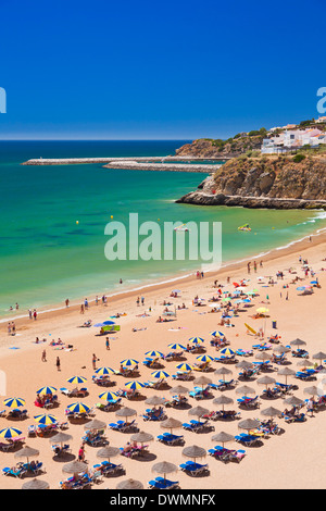Holidaymakers sunbathing under beach umbrellas on the sandy beach at Praia do Tunel, Albufeira Beach, Algarve, Portugal, Europe Stock Photo