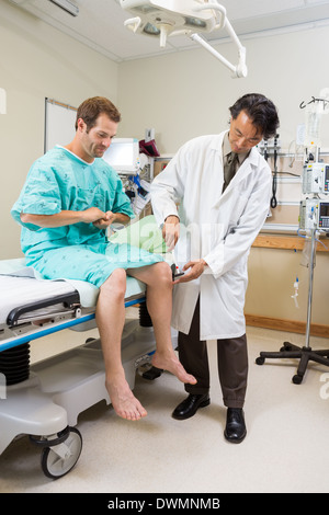 Doctor Examining Patient's Knee With Hammer In Hospital Stock Photo