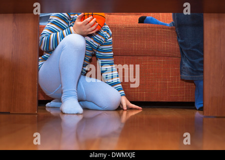 Detail of child with ball sitting on the floor. Stock Photo