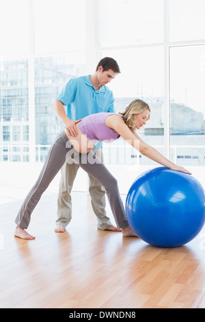 Trainer exercising with pregnant client and exercise ball Stock Photo