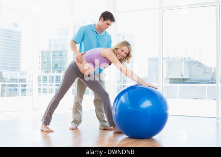 Trainer exercising with smiling pregnant client and exercise ball Stock Photo