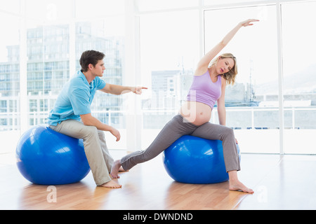 Trainer exercising with blonde pregnant client on exercise balls Stock Photo