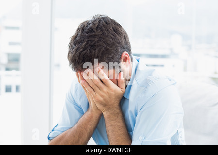 Man with head in hands sitting on the couch Stock Photo