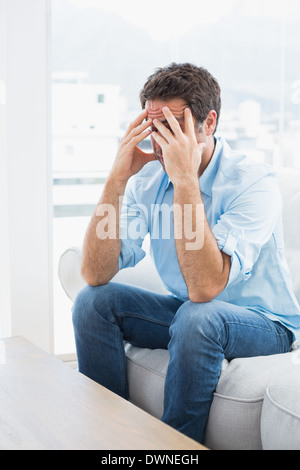 Man with headache sitting on the couch Stock Photo