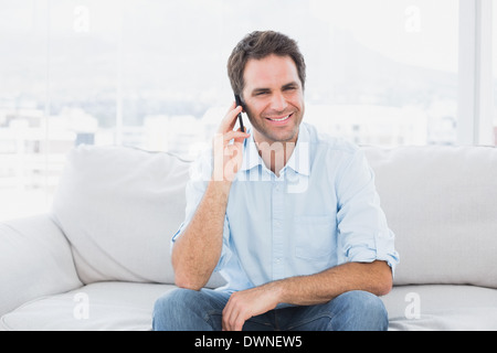 Happy man sitting on the couch chatting on the phone Stock Photo