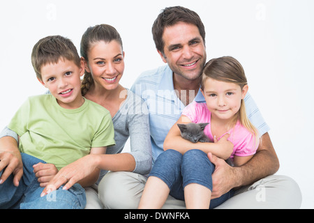 Cute family with pet kitten posing and smiling at camera together Stock Photo