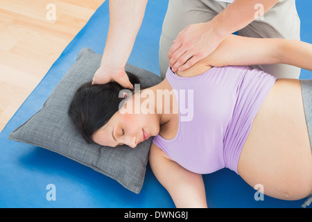 Masseur moving pregnant womans neck and shoulder Stock Photo