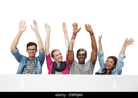 Portrait of four young friends raising hands Stock Photo
