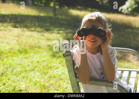 Girl looking through binoculars at park Stock Photo