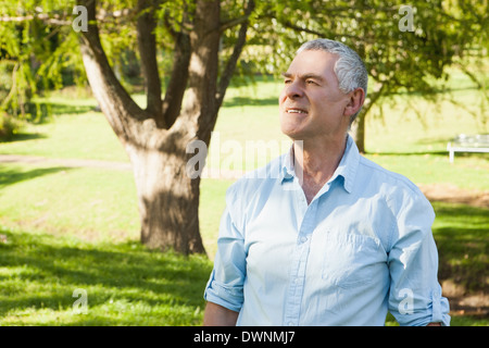 Thoughtful mature man looking away at park Stock Photo