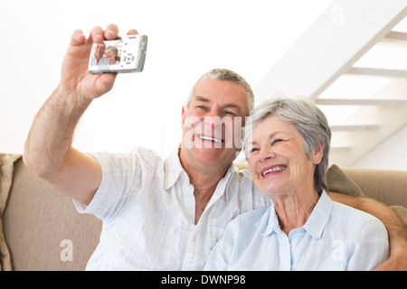 Senior couple sitting on couch taking a selfie Stock Photo