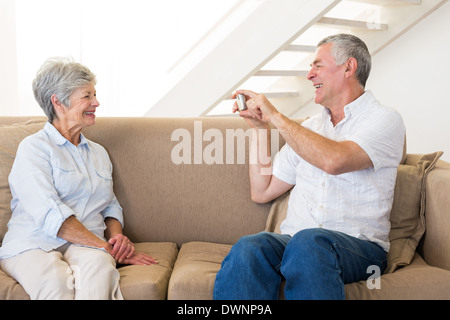 Retired man taking photo of his partner on the couch Stock Photo