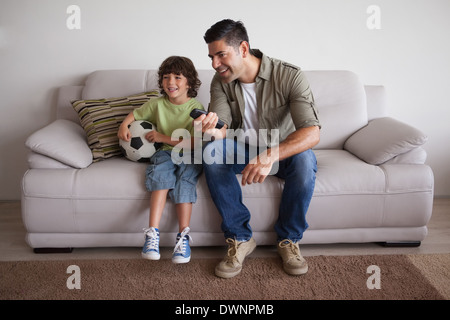 Father and son with football watching tv in the living room Stock Photo